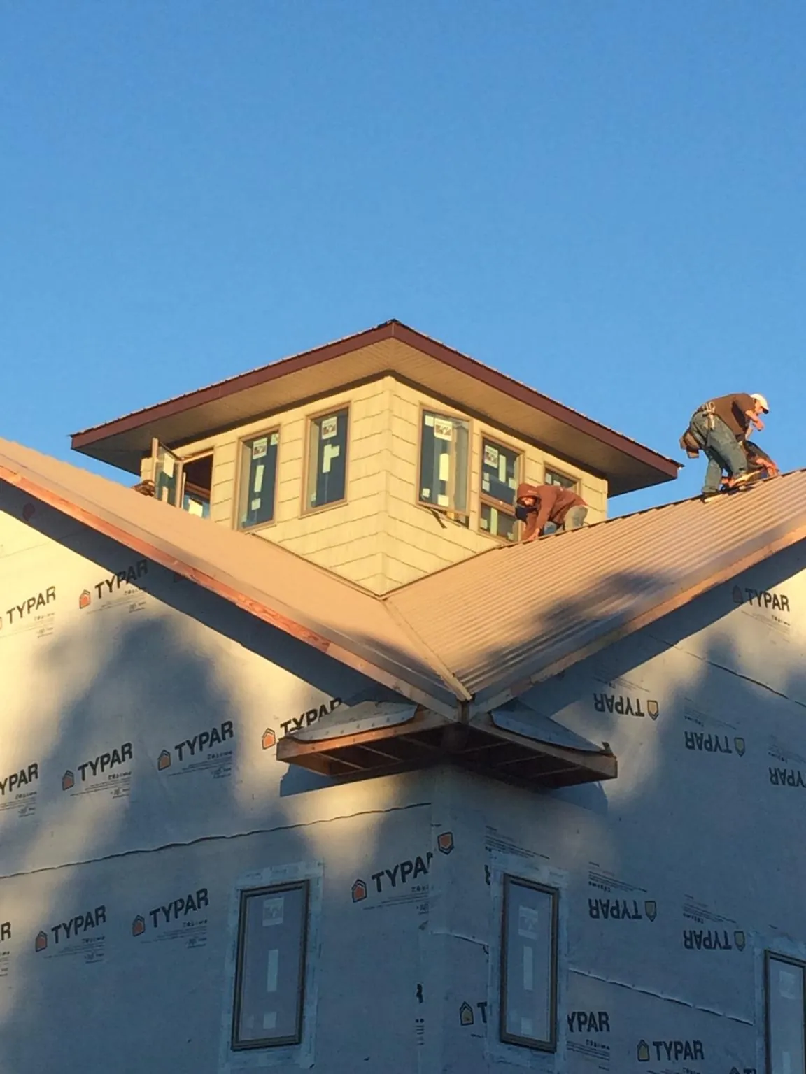 Roofers working around a rooftop cupola on a new metal roof at sunset — Roof Waterproofing in Elmira by Roofing Brothers